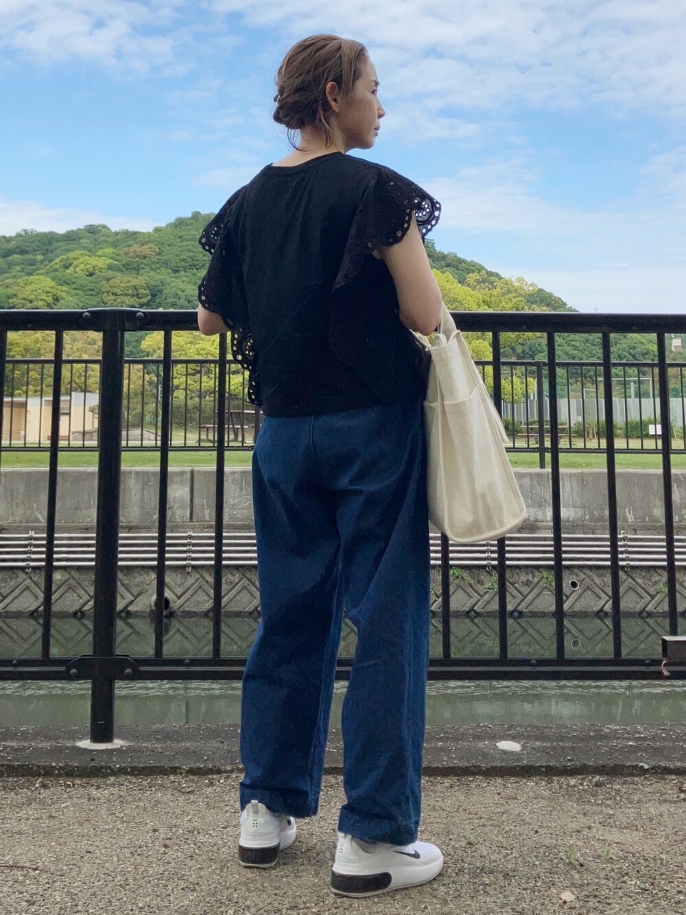 ブラック系のTシャツ/カットソー、ブルー系のデニムパンツ、ホワイト系のスニーカーを着用したレディースの春コーディネートの2枚目の写真