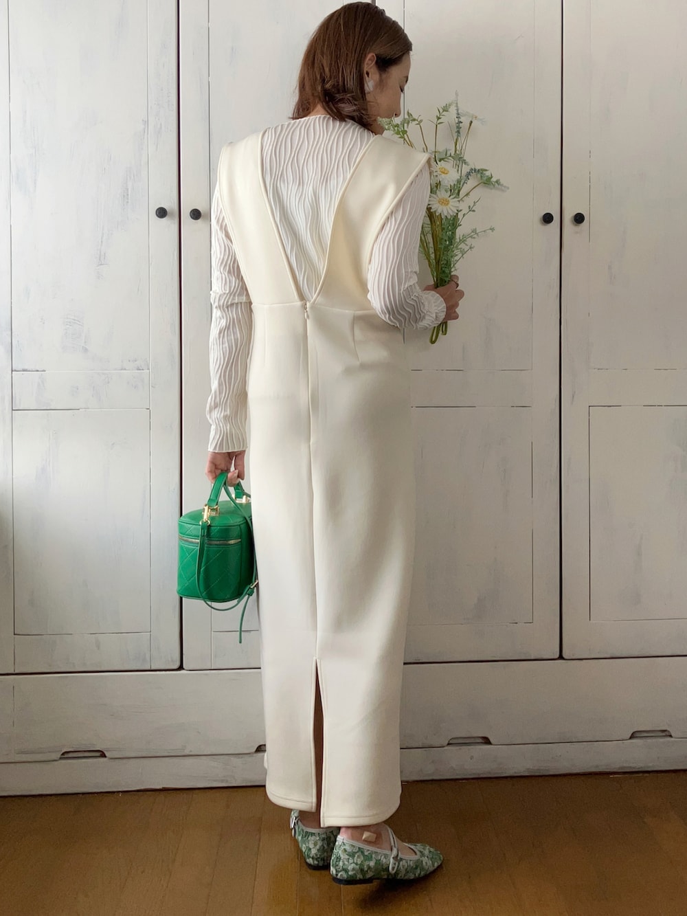 ホワイト系のジャンパースカート、ホワイト系のTシャツ/カットソー、グリーン系のショルダーバッグを着用したレディースの冬コーディネートの2枚目の写真