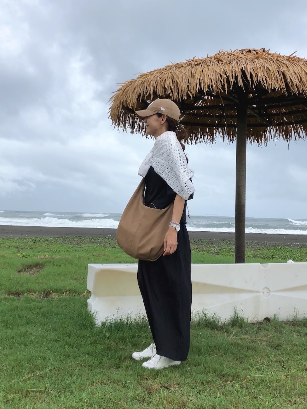 ブラック系のトップス、ベージュ系のショルダーバッグ、ブラック系のパンツを着用したレディースの夏コーディネートの4枚目の写真