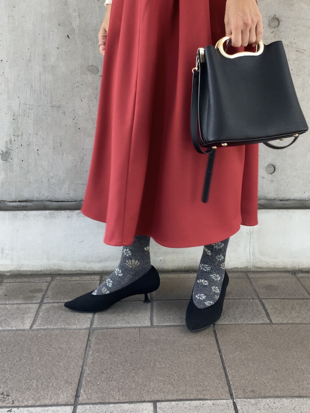 ホワイト系のニット/セーター、レッド系のスカート、ブラック系のハンドバッグを着用したレディースの秋コーディネートの3枚目の写真
