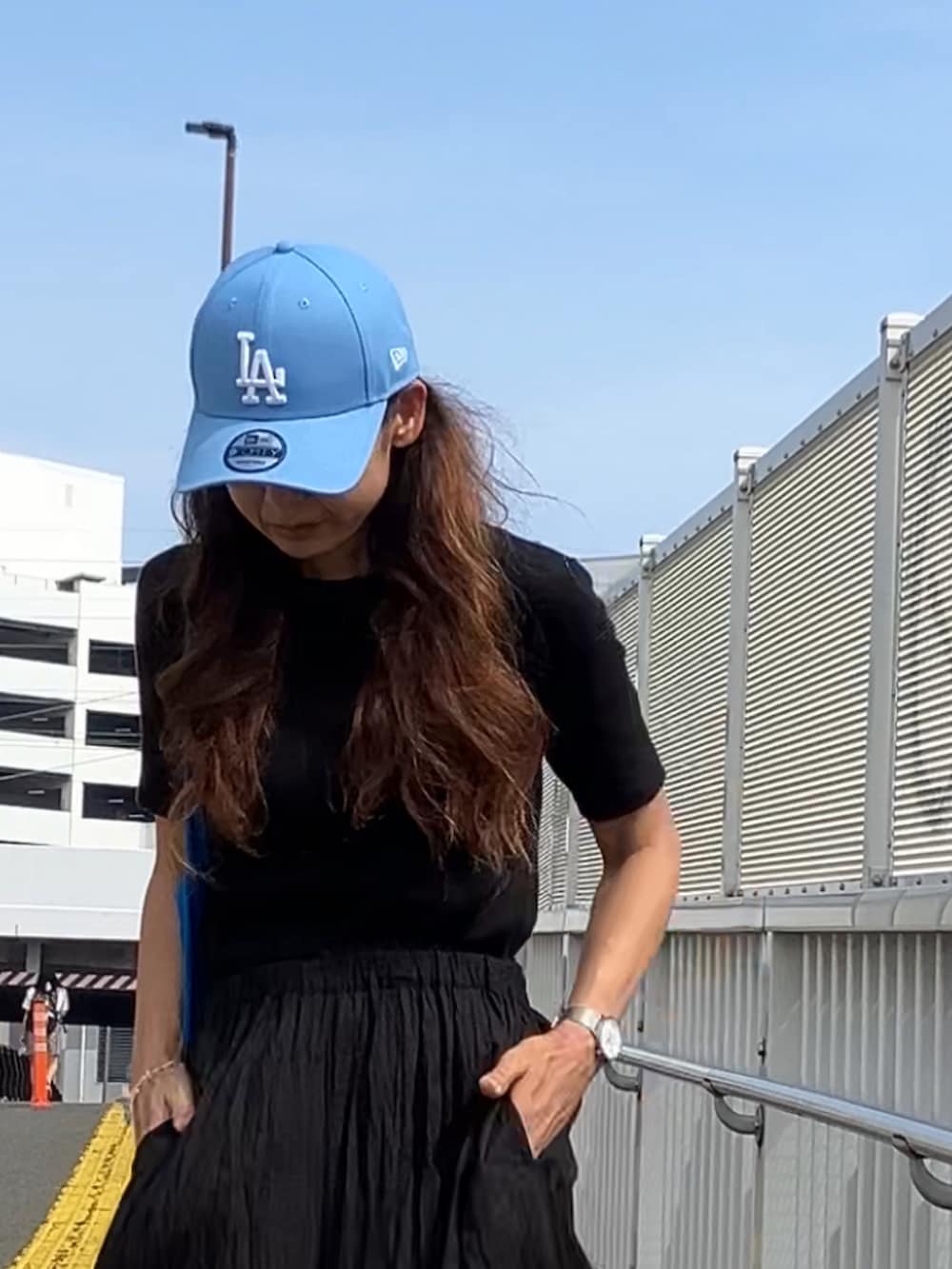 ブラック系のパンツ、ブラック系のTシャツ/カットソー、ブルー系のキャップを着用したレディースの夏コーディネートの2枚目の写真