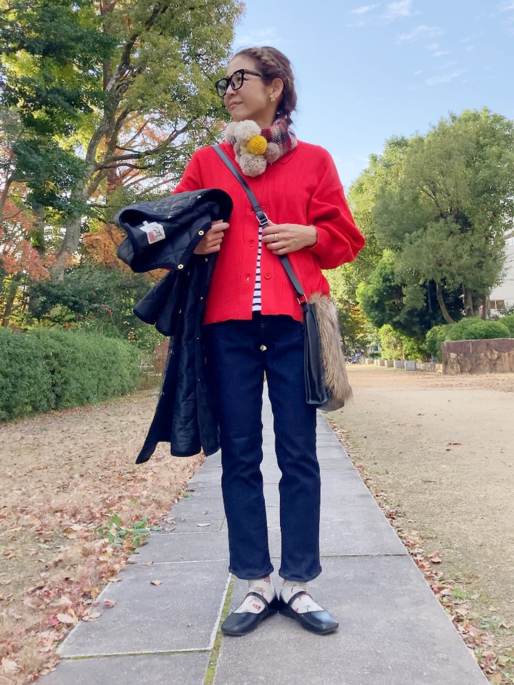 ブラック系のその他アウター、レッド系のカーディガン/ボレロ、ブルー系のデニムパンツを着用したレディースの冬コーディネートの2枚目の写真