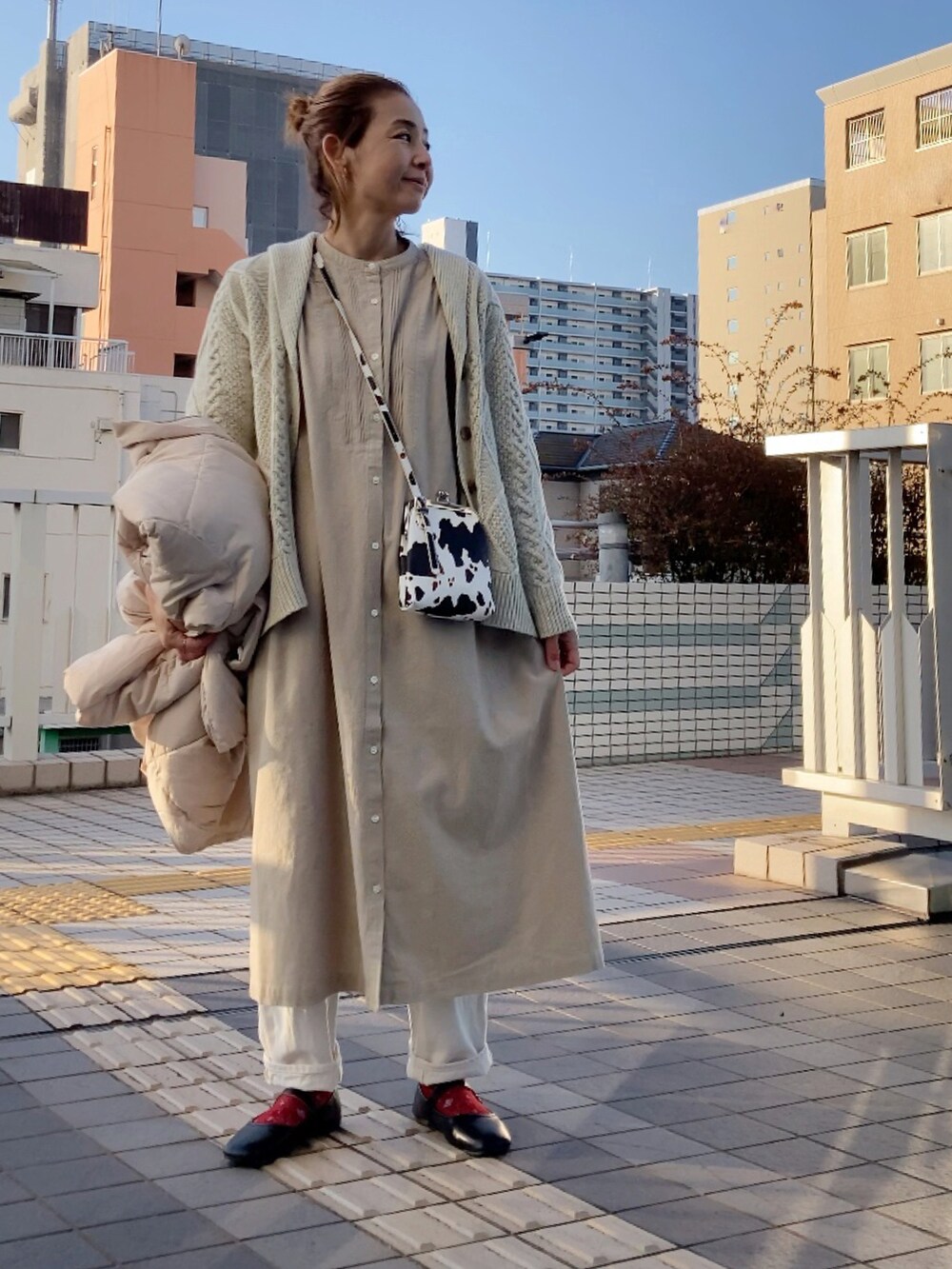 ホワイト系のカーディガン/ボレロ、ベージュ系のワンピース、ホワイト系のダウンジャケット/コートを着用したレディースの冬コーディネートの4枚目の写真