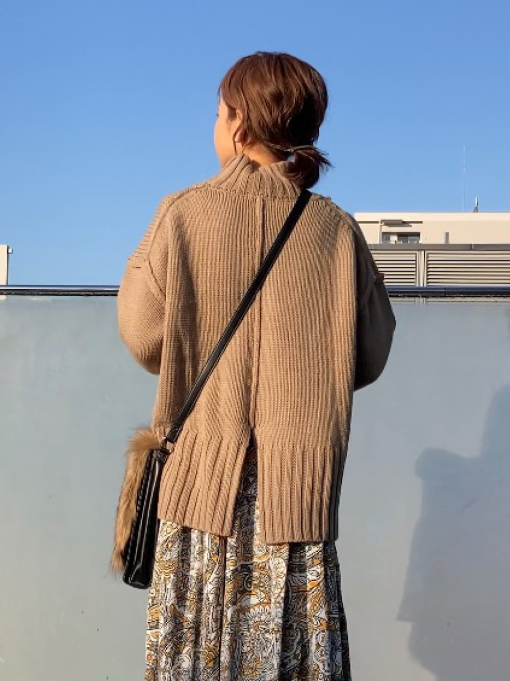 ベージュ系のニット/セーター、イエロー系のワンピース、ブラウン系のショルダーバッグを着用したレディースの秋コーディネートの3枚目の写真