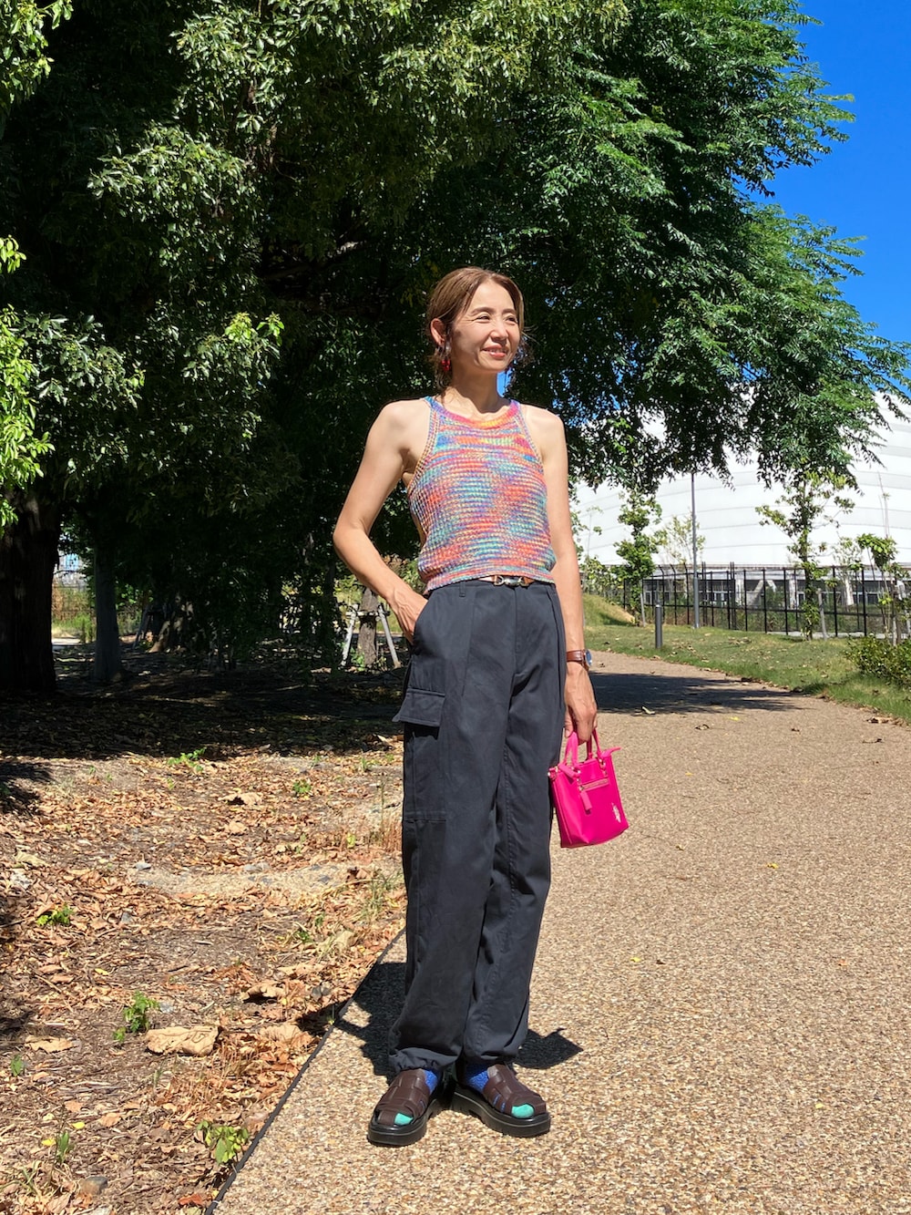 オレンジ系のその他トップス、ピンク系のショルダーバッグ、ブラック系のカーゴパンツを着用したレディースの夏コーディネートの2枚目の写真