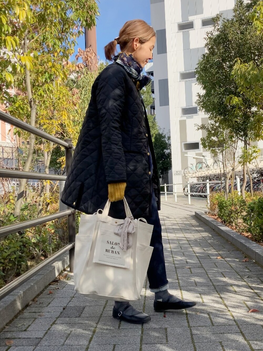 ブラック系のその他アウター、ホワイト系のトートバッグ、ブルー系のデニムパンツを着用したレディースの冬コーディネートの3枚目の写真