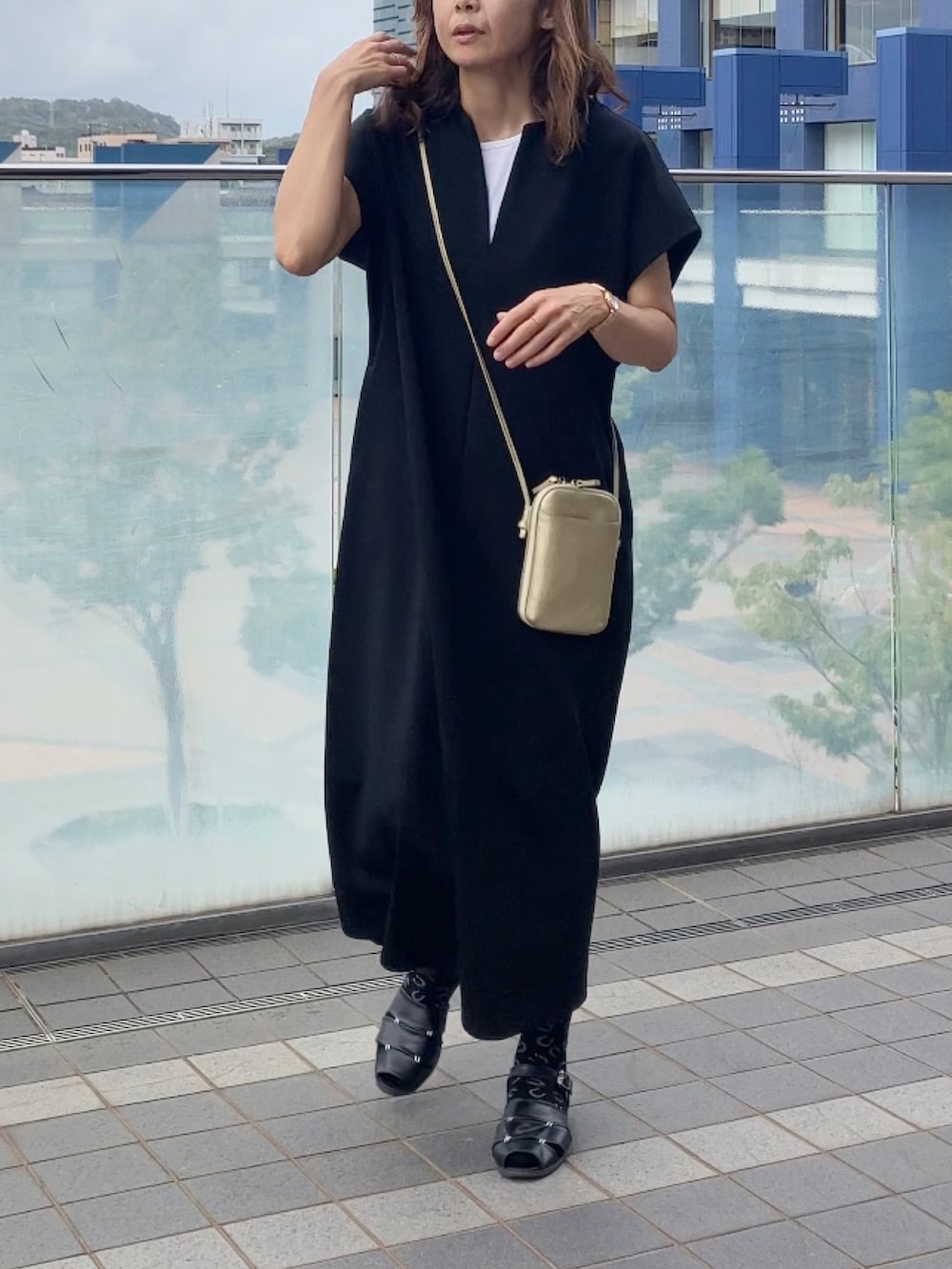 ブラック系のワンピース、ゴールド系のバッグ、ブラック系のサンダルを着用したレディースの秋コーディネートの2枚目の写真