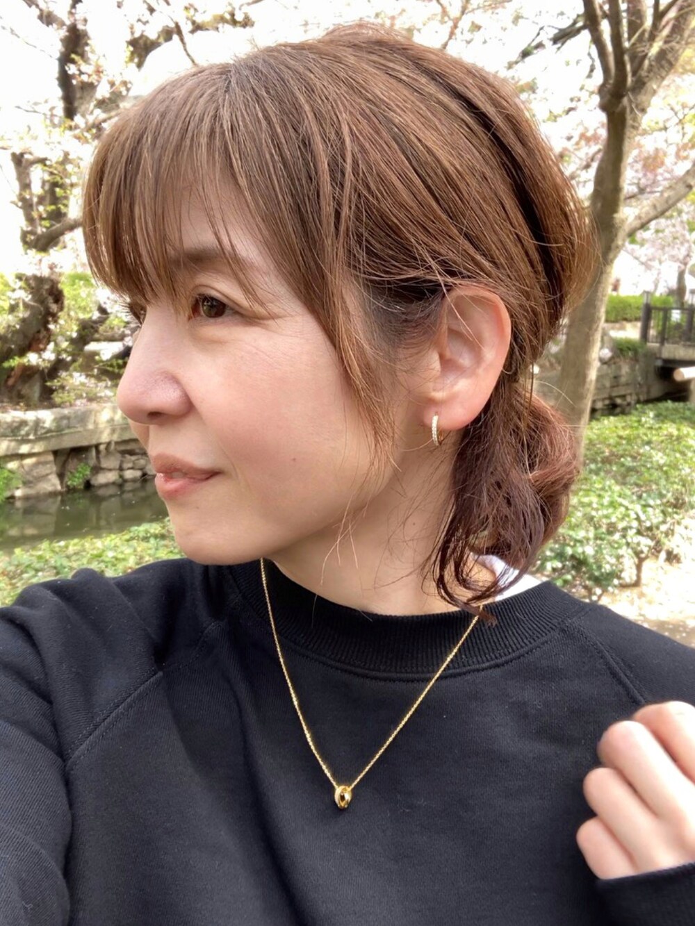 ブラック系のスウェット、レッド系のハンドバッグ、グリーン系のスカートを着用したレディースの春コーディネートの2枚目の写真