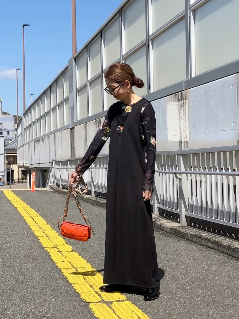 ブラック系のジャンパースカート、ブラック系のTシャツ/カットソー、オレンジ系のショルダーバッグを着用したレディースの春コーディネートの3枚目の写真