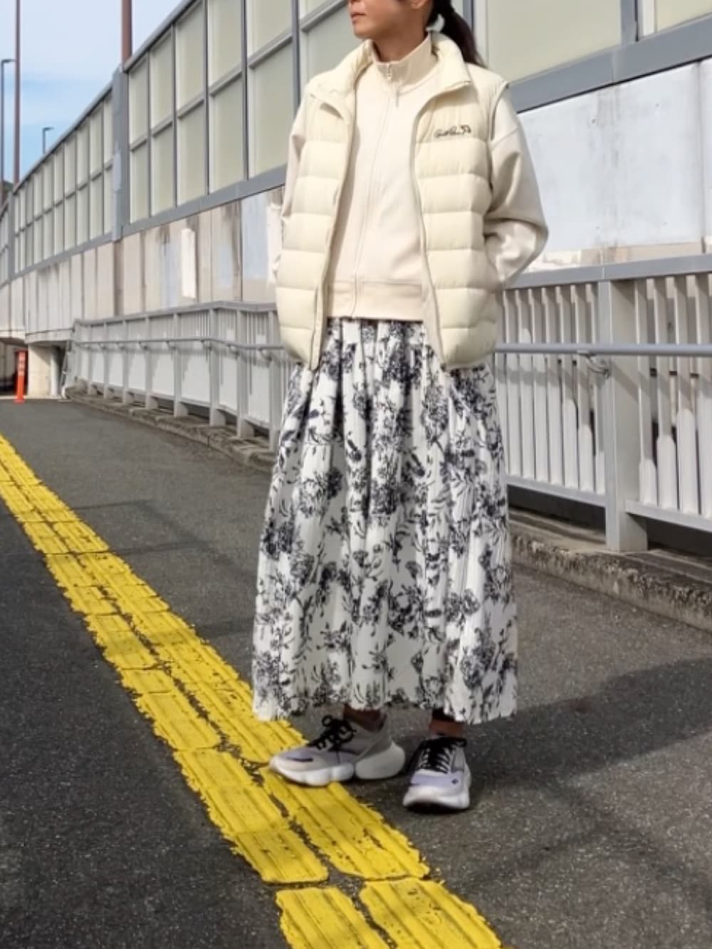 ホワイト系のダウンベストを着用したレディースの秋コーディネートの2枚目の写真
