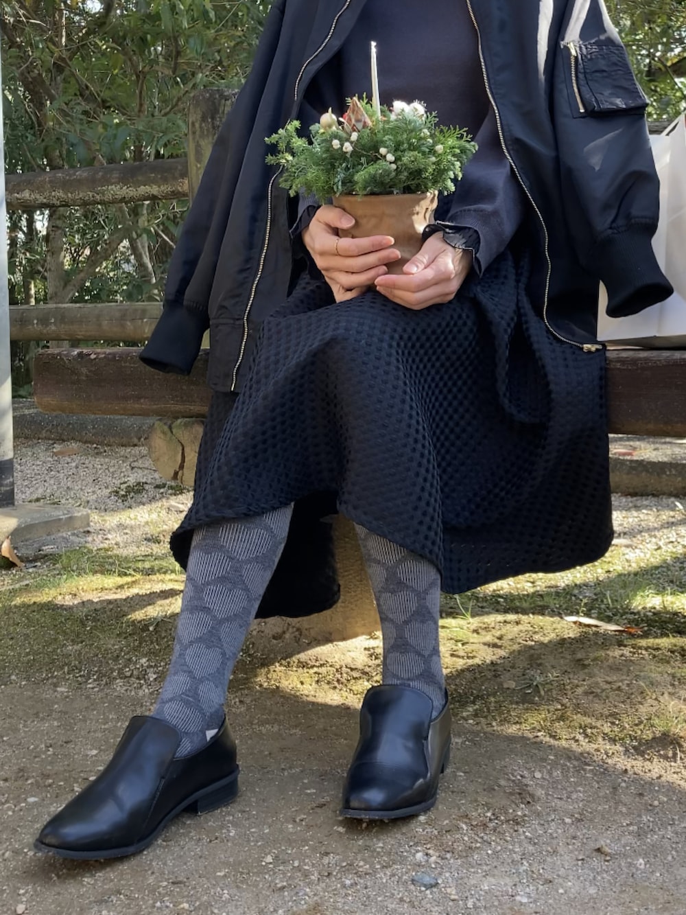 ブラック系のブルゾン、グレー系のニット/セーター、ブラック系のスカートを着用したレディースの冬コーディネートの4枚目の写真