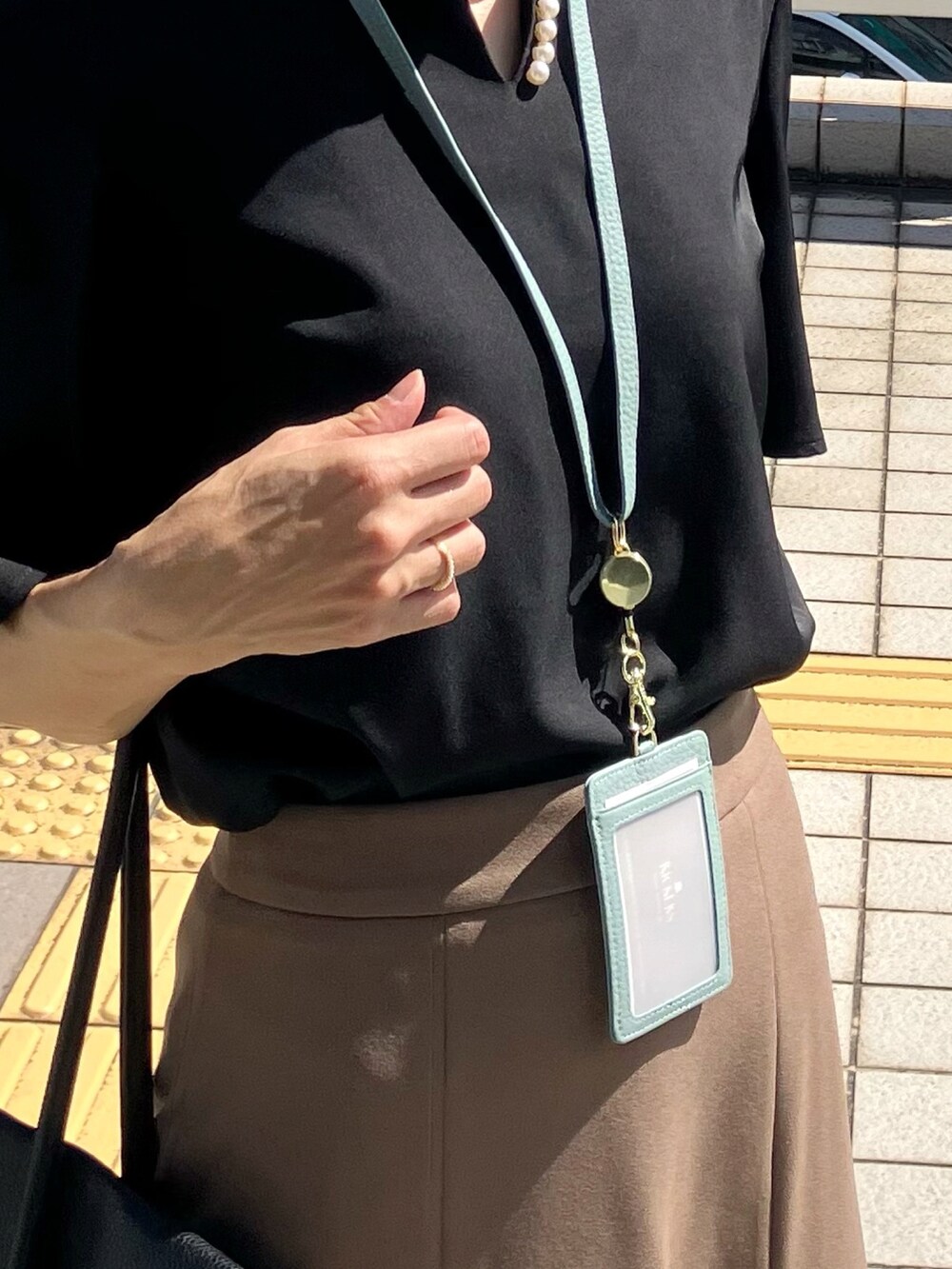 ブラック系のシャツ/ブラウス、ブラウン系のスカート、ブラック系のビジネスバッグを着用したレディースの夏コーディネートの2枚目の写真