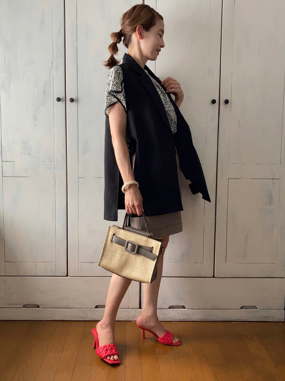 ブラック系のベスト、ホワイト系のシャツ/ブラウス、ベージュ系のパンツを着用したレディースの夏コーディネートの2枚目の写真