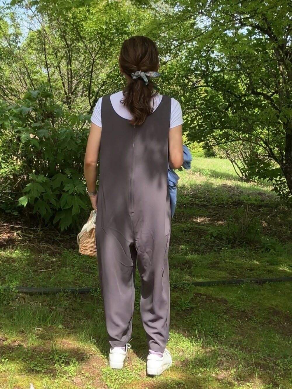 グレー系のサロペット/オーバーオール、ベージュ系のかごバッグ、ブルー系のカーディガン/ボレロを着用したレディースの春コーディネートの3枚目の写真