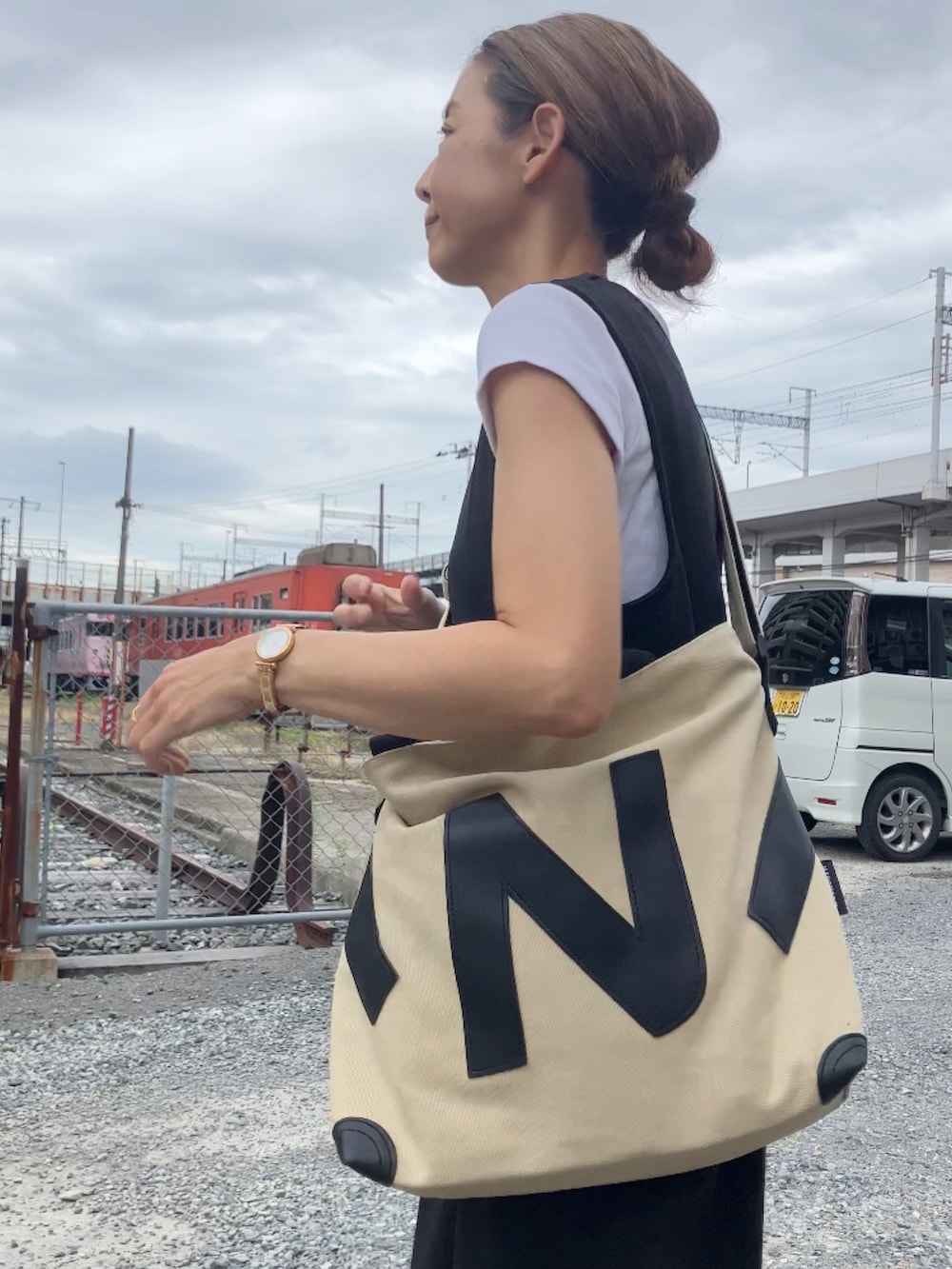 ブラック系のつなぎ/オールインワン、ホワイト系のTシャツ/カットソー、ベージュ系のトートバッグを着用したレディースの秋コーディネートの2枚目の写真