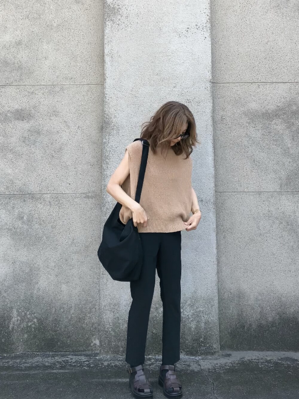 ベージュ系のベスト、ブラック系のパンツ、ブラック系のショルダーバッグを着用したレディースの夏コーディネートの2枚目の写真