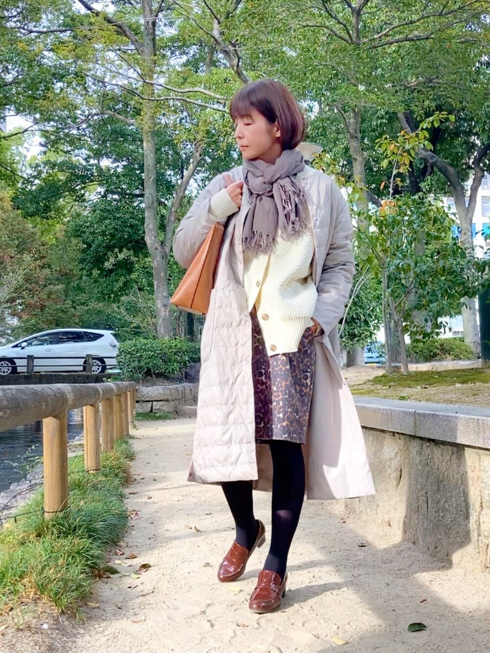 ベージュ系のダウンジャケット/コート、ホワイト系のカーディガン/ボレロ、ブラウン系のスカートを着用したレディースの秋コーディネートの2枚目の写真