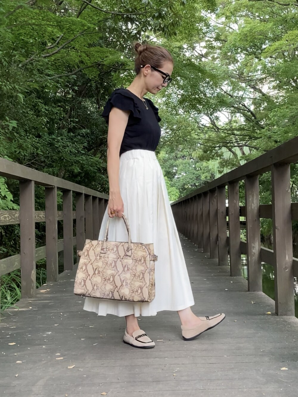 ホワイト系のスカート、ベージュ系のシューズ、ブラック系のニット/セーターを着用したレディースの夏コーディネートの3枚目の写真