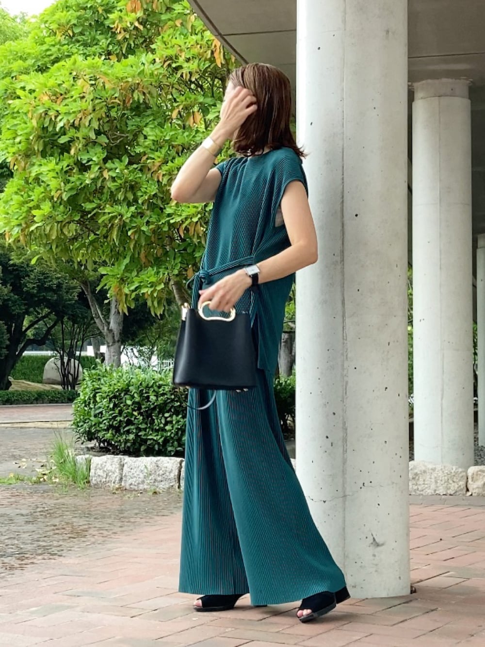 グリーン系のパンツ、ブラック系のハンドバッグ、ブラック系のサンダルを着用したレディースの夏コーディネートの3枚目の写真
