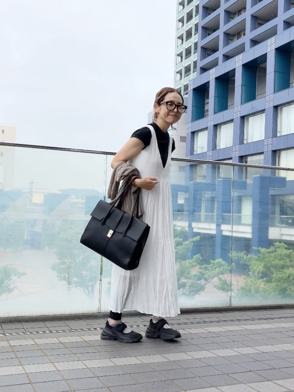 ホワイト系のワンピース、ブラック系のビジネスバッグ、ブラック系のシューズを着用したレディースの夏コーディネートの3枚目の写真