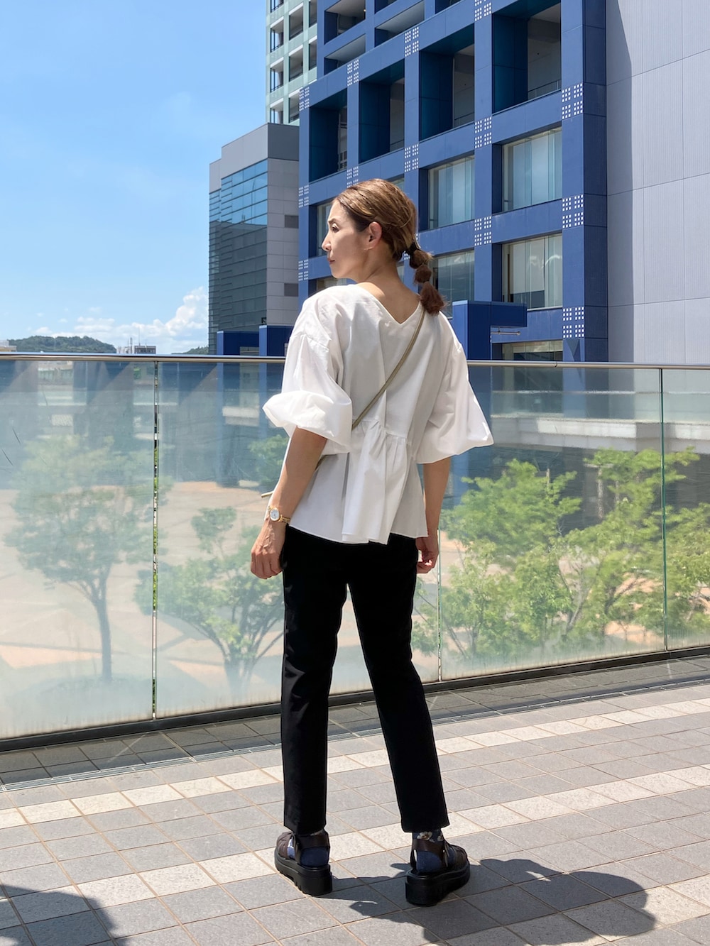 ホワイト系のシャツ/ブラウス、ブラック系のパンツ、ゴールド系のバッグを着用したレディースの夏コーディネートの3枚目の写真