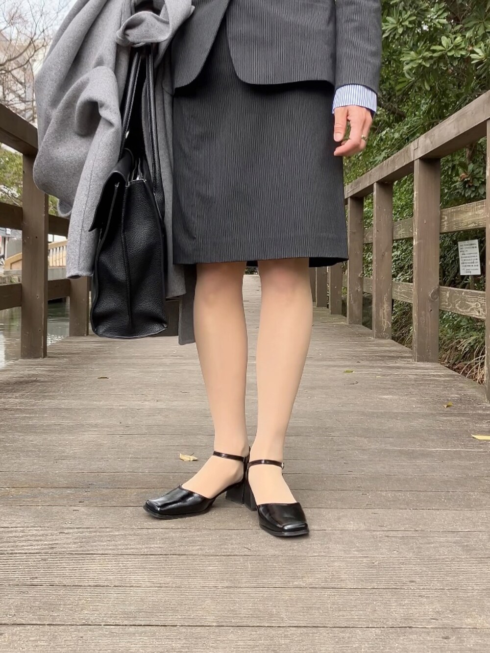 ブラック系のパンプス、グレー系のフォーマルスーツ/小物、ブラック系のビジネスバッグを着用したレディースの春コーディネートの2枚目の写真