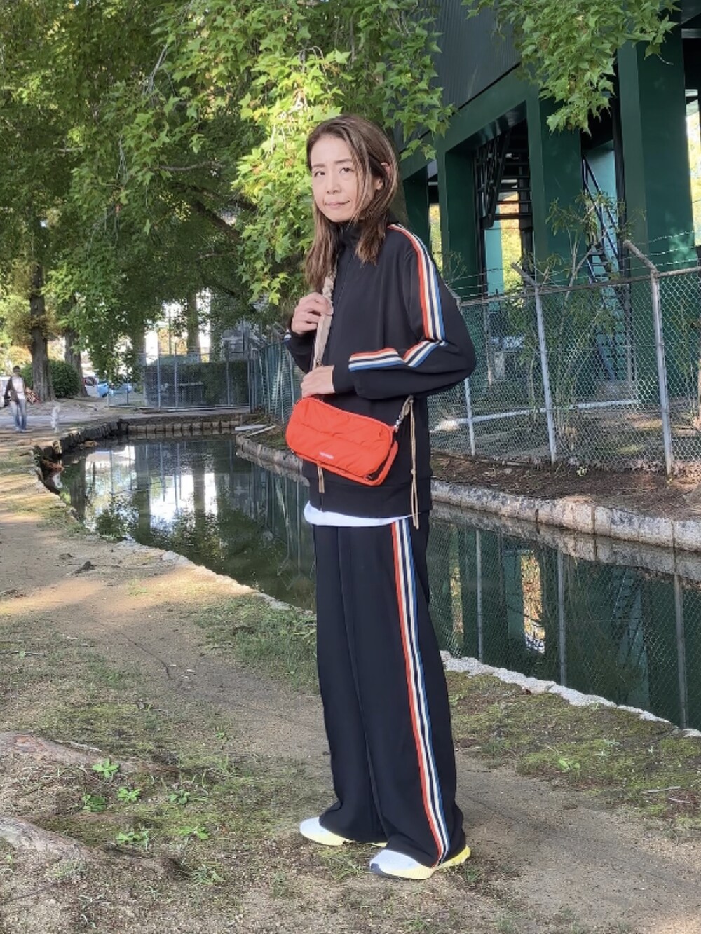 ブラック系のジャージ、オレンジ系のショルダーバッグ、ブラック系のレギンス/スパッツを着用したレディースの秋コーディネートの2枚目の写真