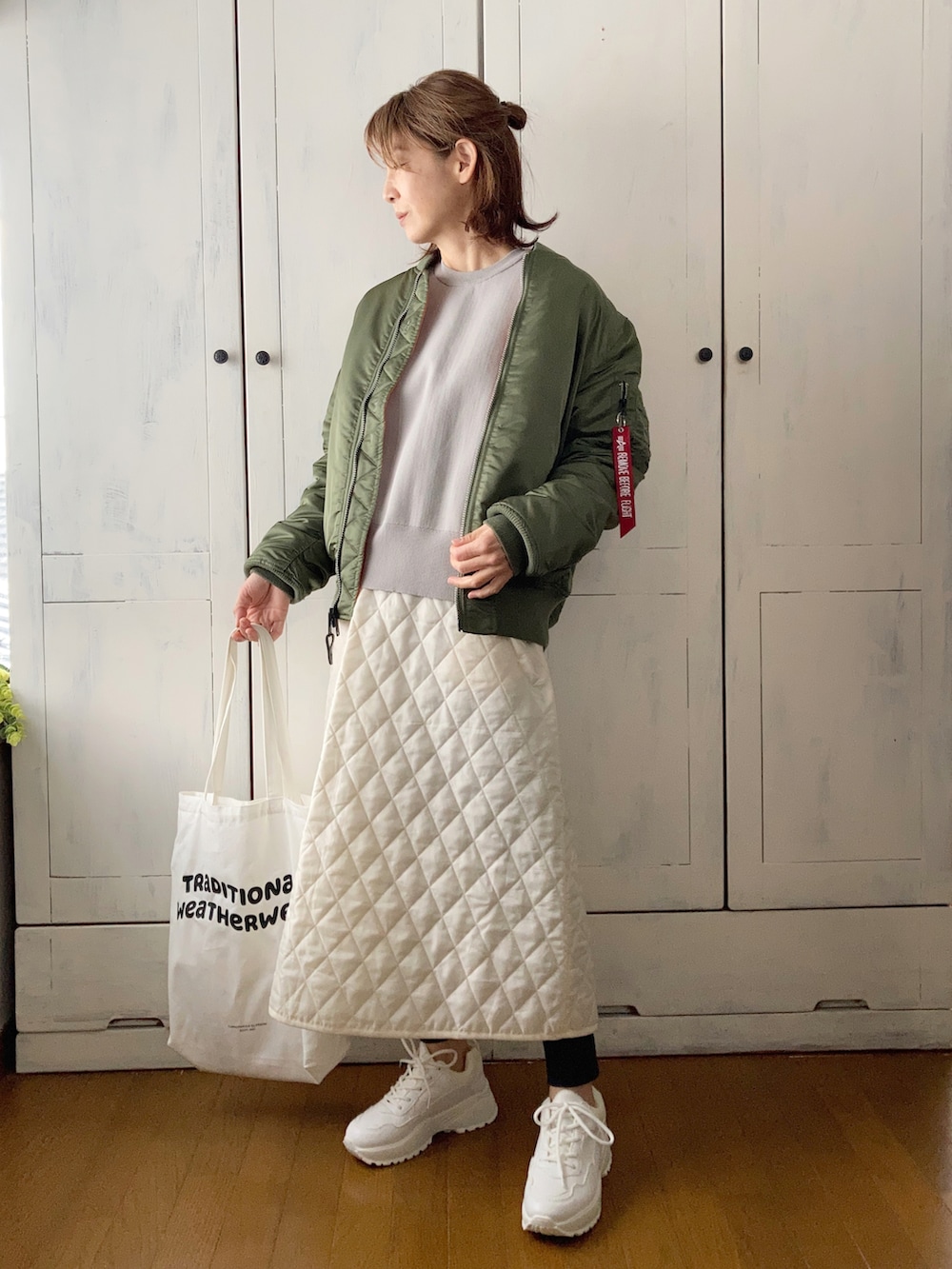 グリーン系のMA-1、グレー系のカーディガン/ボレロ、ホワイト系のスカートを着用したレディースの冬コーディネートの3枚目の写真