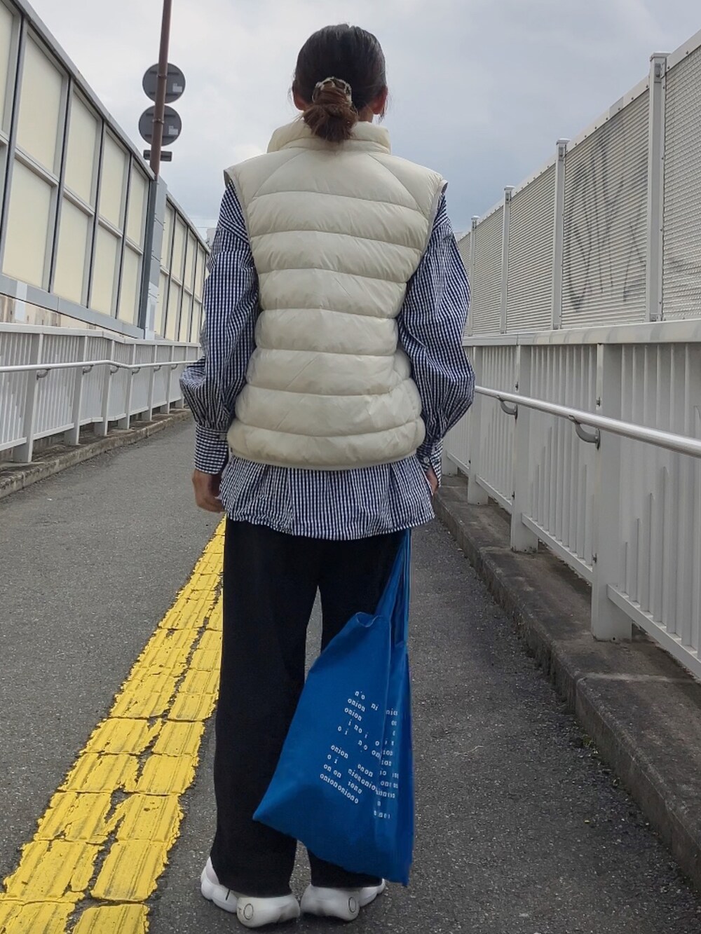 ホワイト系のダウンベスト、ブルー系のトートバッグを着用したレディースの秋コーディネートの3枚目の写真
