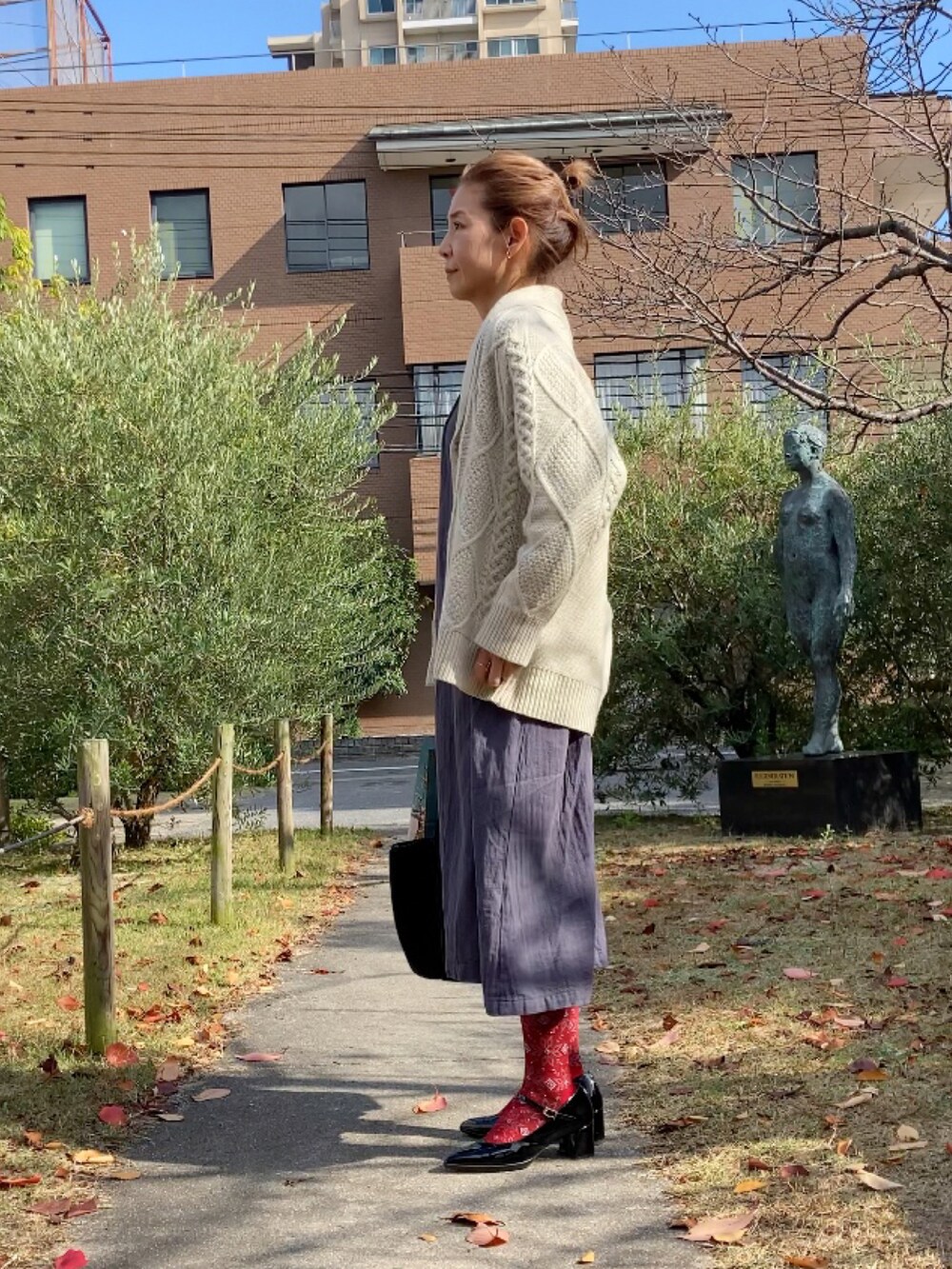 ホワイト系のカーディガン/ボレロ、グレー系のワンピース/ドレス、ブラック系のシューズを着用したレディースの秋コーディネートの3枚目の写真