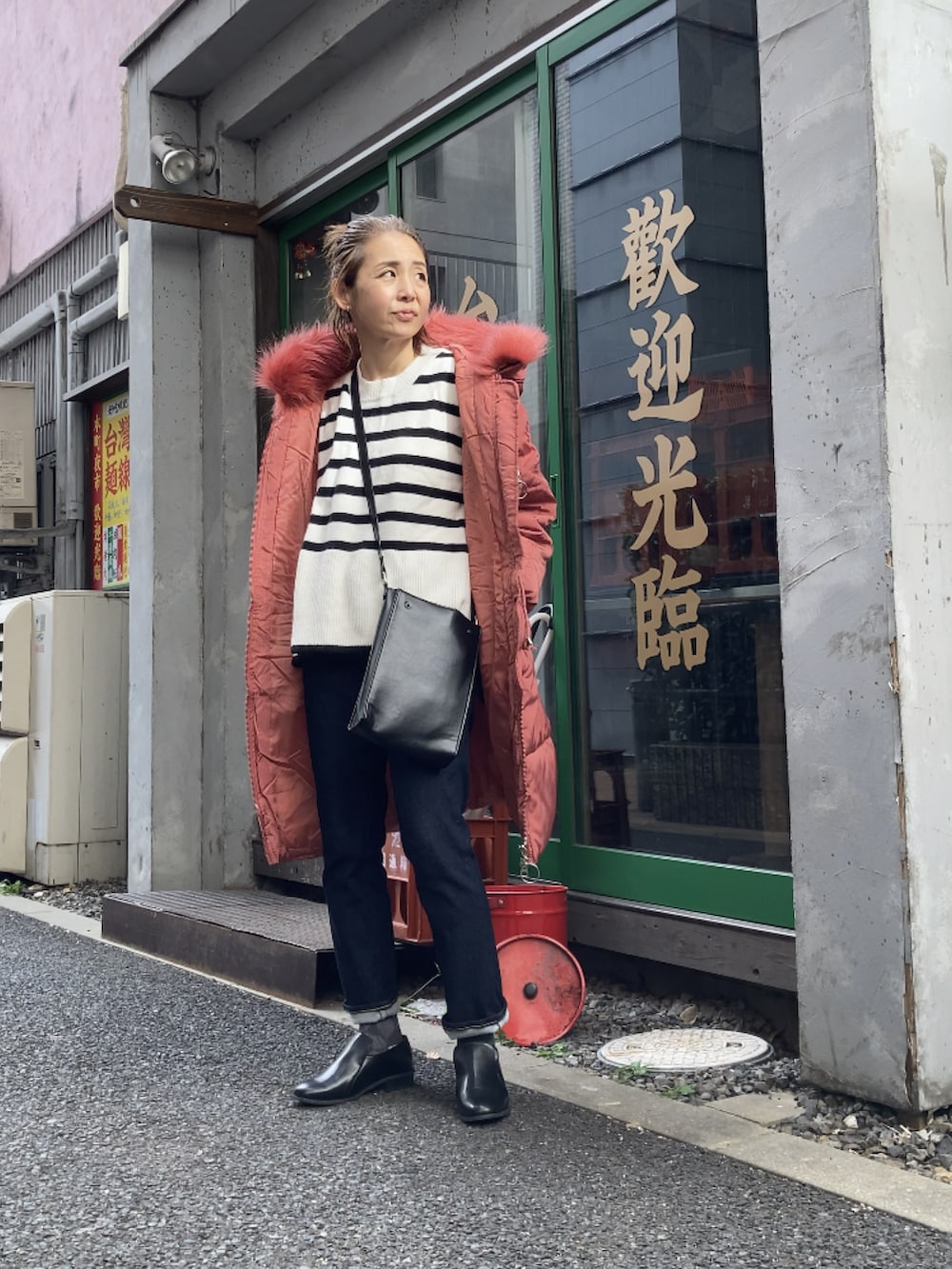 レッド系のダウンジャケット/コート、ブルー系のデニムパンツ、ブラック系のローファーを着用したレディースの冬コーディネートの5枚目の写真