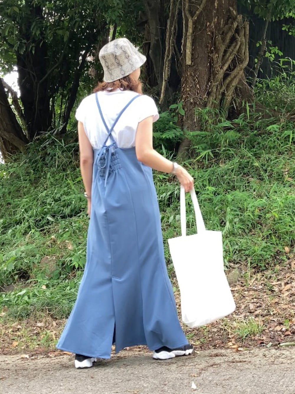 ブルー系のワンピース、ホワイト系のTシャツ/カットソー、ブラック系のサンダルを着用したレディースの夏コーディネートの2枚目の写真