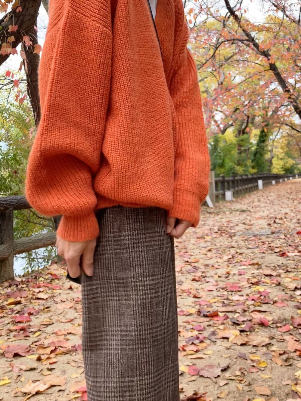 ブラウン系のパンツ、オレンジ系のカーディガン/ボレロ、ブラウン系のショルダーバッグを着用したレディースの秋コーディネートの3枚目の写真