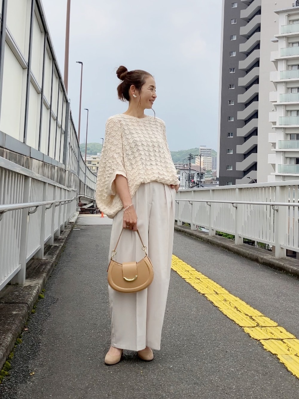 ベージュ系のニット/セーター、ベージュ系のハンドバッグ、ホワイト系のその他パンツを着用したレディースの春コーディネートの3枚目の写真