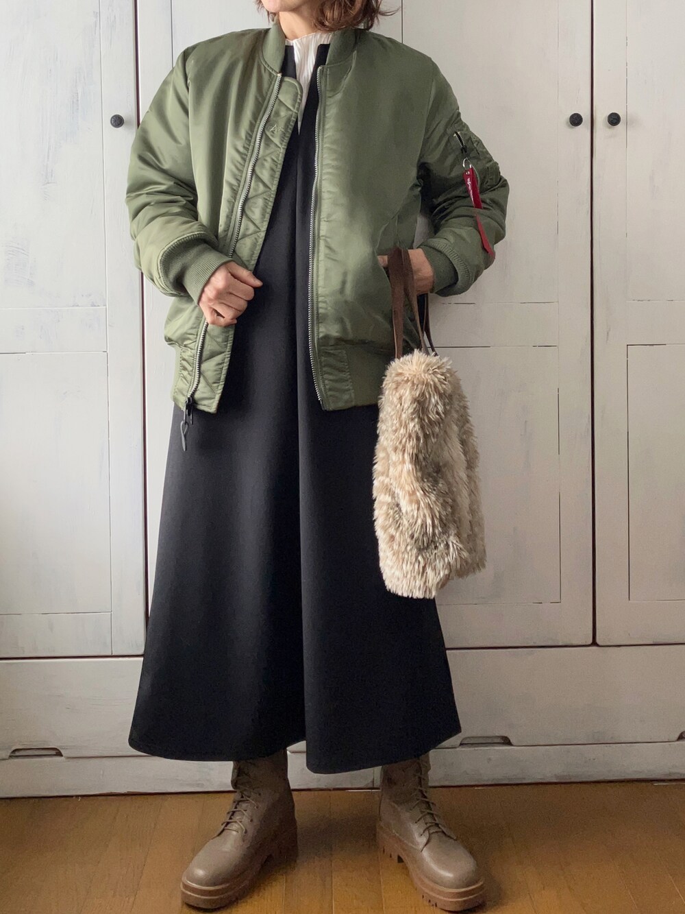グリーン系のMA-1、ブラック系のワンピース、ホワイト系のTシャツ/カットソーを着用したレディースの冬コーディネートの2枚目の写真