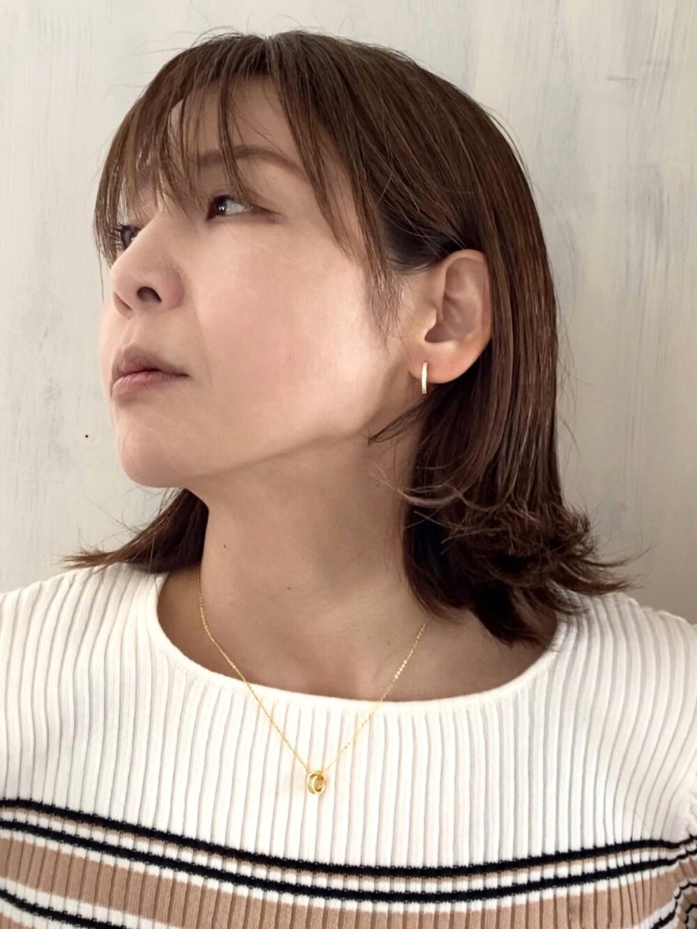 ホワイト系のニット/セーター、オレンジ系のスカート、ブラウン系のかごバッグを着用したレディースの春コーディネートの3枚目の写真