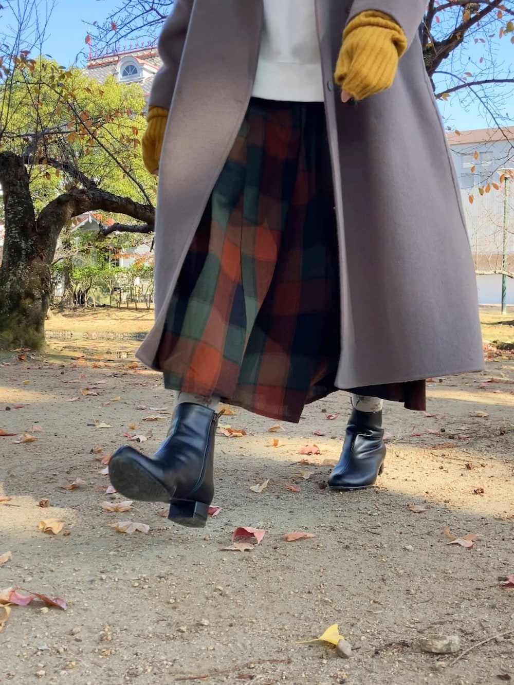 ブラウン系のチェスターコート、ブラック系のブーツ、ホワイト系のスウェットを着用したレディースの秋コーディネートの2枚目の写真