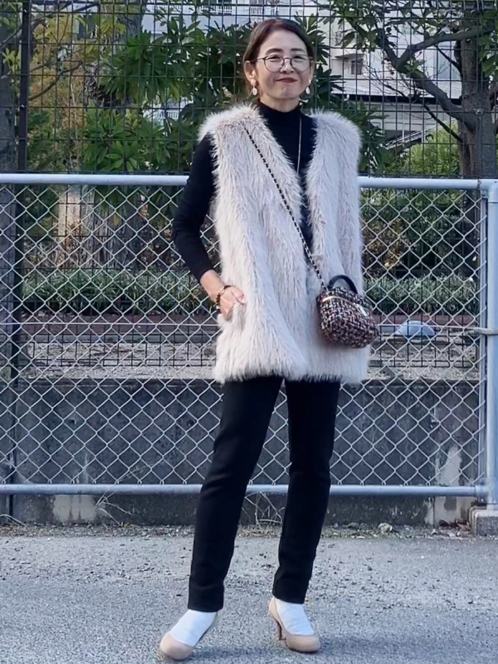 ブラック系のトップス、ベージュ系のベスト、その他のハンドバッグを着用したレディースの冬コーディネートの4枚目の写真