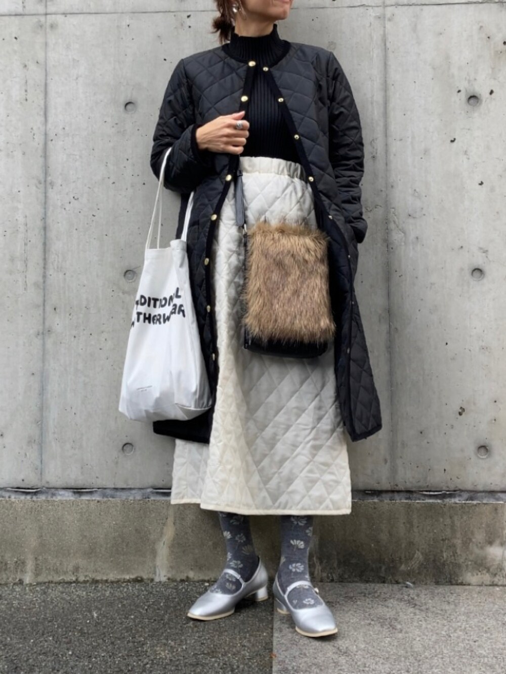 ブラック系のその他アウター、ホワイト系のトートバッグ、ブラック系のニット/セーターを着用したレディースの秋コーディネートの4枚目の写真