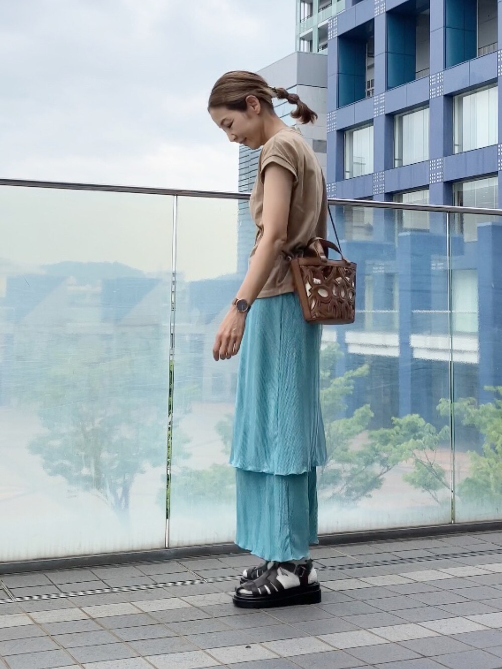 ブルー系のスカート、ベージュ系のTシャツ/カットソー、ブラウン系のサンダルを着用したレディースの夏コーディネートの3枚目の写真