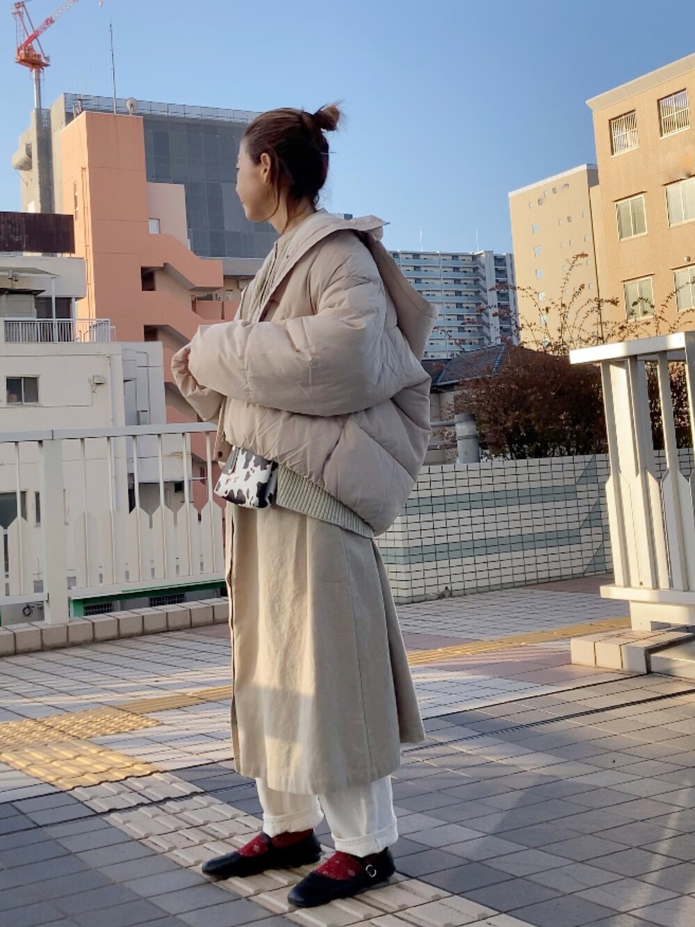 ホワイト系のカーディガン/ボレロ、ベージュ系のワンピース、ホワイト系のダウンジャケット/コートを着用したレディースの冬コーディネートの2枚目の写真