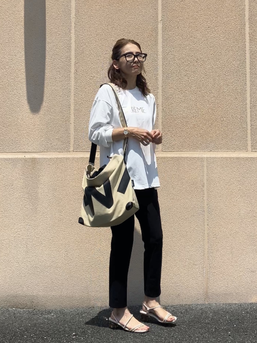 ホワイト系のTシャツ/カットソー、ブラック系のパンツ、ベージュ系のトートバッグを着用したレディースの夏コーディネートの3枚目の写真