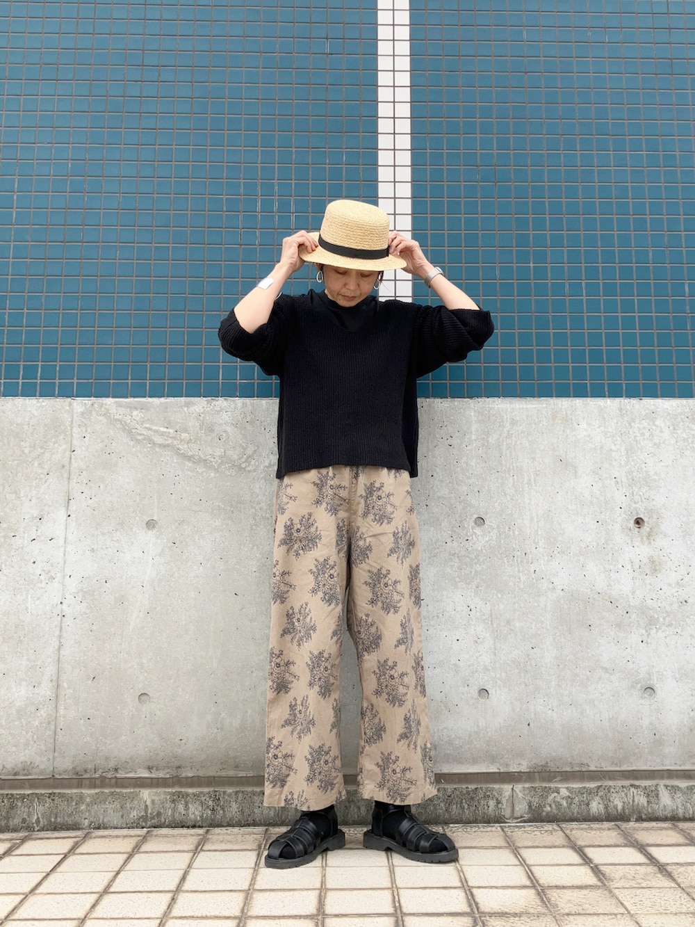 ベージュ系のパンツ、ブラック系のニット/セーター、ブラック系のサンダルを着用したレディースの春コーディネートの3枚目の写真