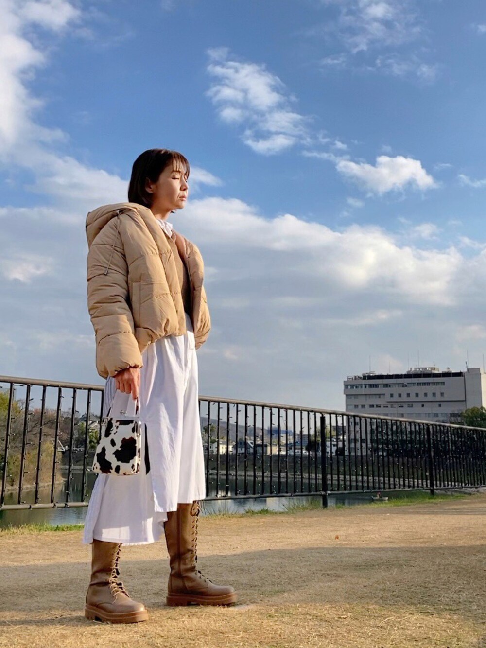 ベージュ系のダウンジャケット/コート、ブラウン系のニット/セーター、ホワイト系のワンピースを着用したレディースの冬コーディネートの2枚目の写真