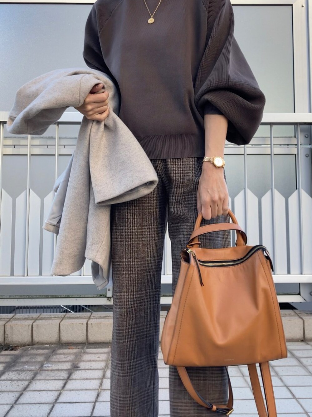 ベージュ系のノーカラーコート、ブラウン系のニット/セーター、ブラウン系のパンツを着用したレディースの秋コーディネートの4枚目の写真