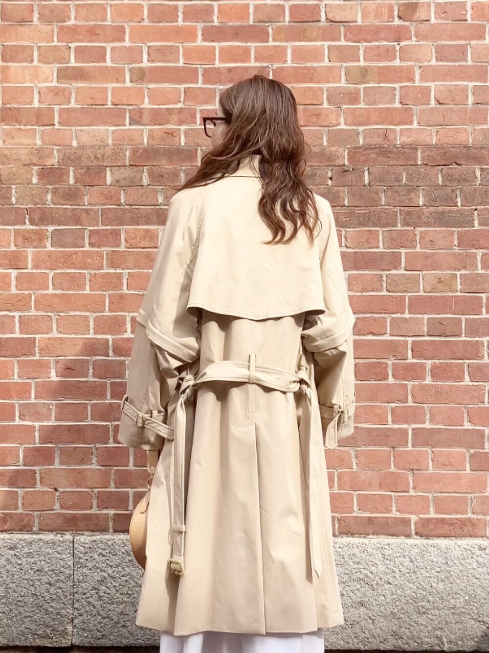 ベージュ系のトレンチコート、ベージュ系のハンドバッグ、ブラック系のシューズを着用したレディースの春コーディネートの4枚目の写真