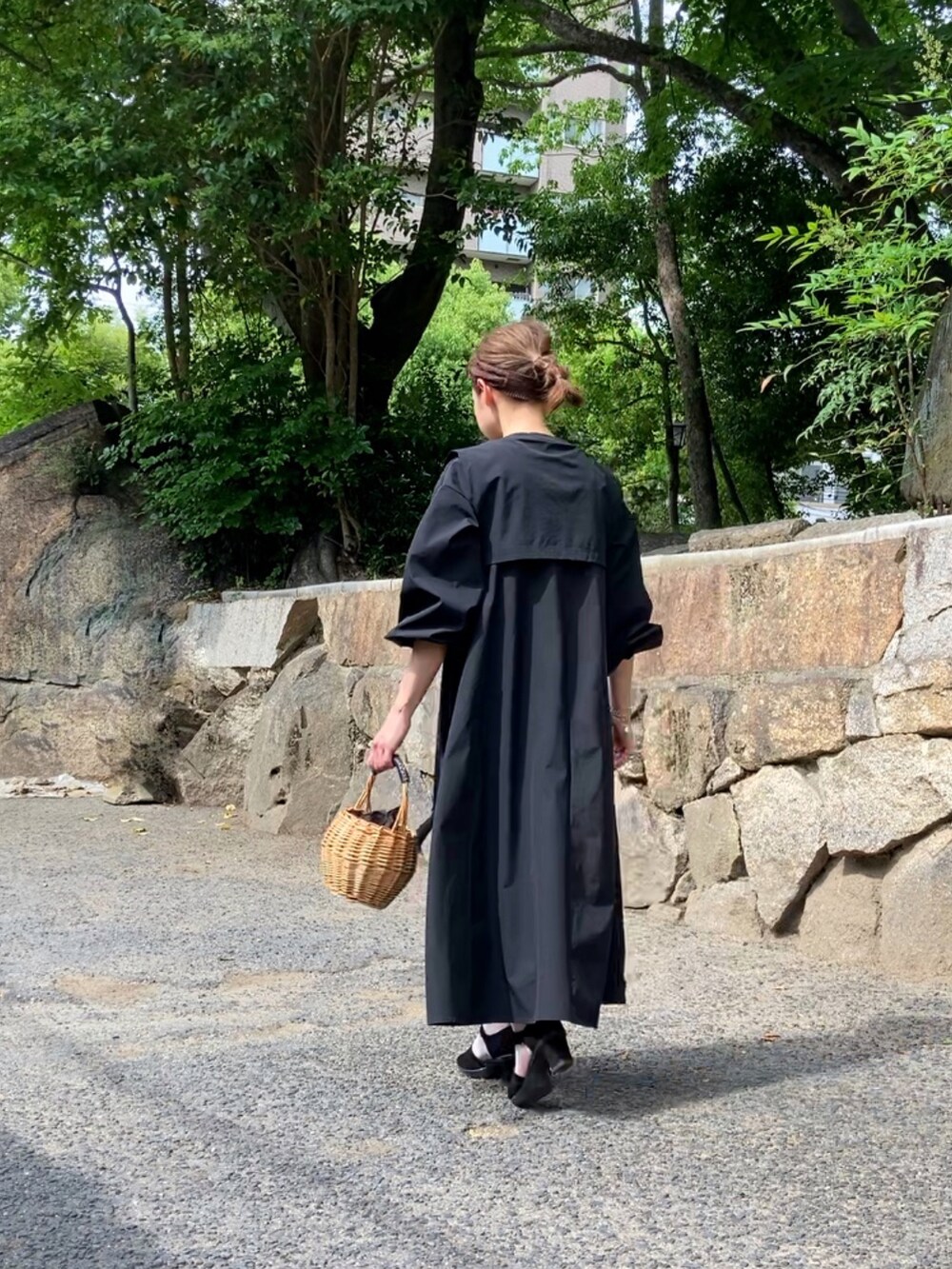 ブラック系のシャツワンピース、ブラック系のサンダル、ベージュ系のかごバッグを着用したレディースの春コーディネートの3枚目の写真