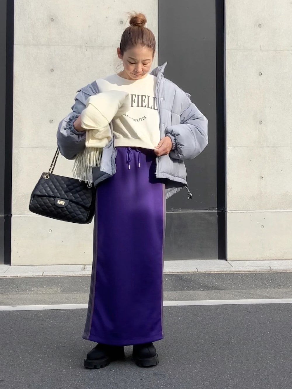 パープル系のスカート、ホワイト系のスウェット、グレー系のダウンジャケット/コートを着用したレディースの冬コーディネートの4枚目の写真