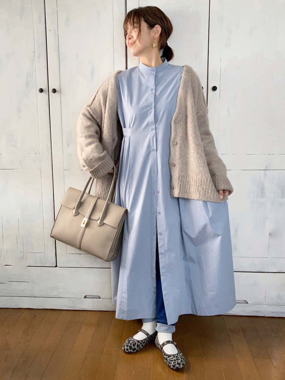 ブルー系のシャツワンピース、ベージュ系のカーディガン/ボレロ、ベージュ系のビジネスバッグを着用したレディースの冬コーディネートの2枚目の写真
