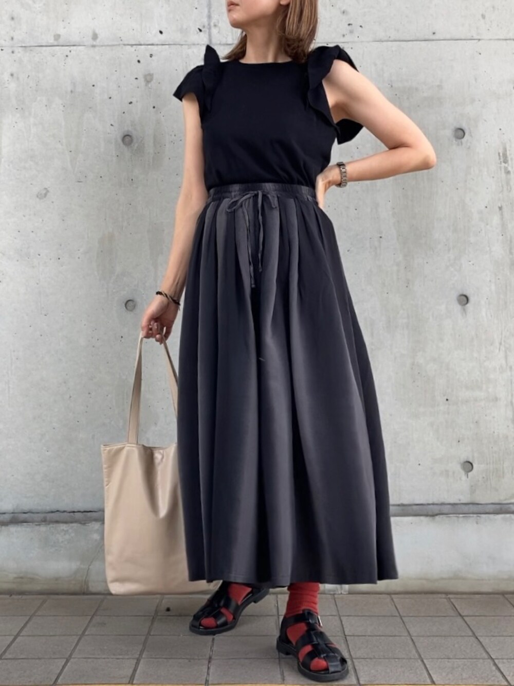 グレー系のパンツ、ブラック系のニット/セーター、ブラック系のサンダルを着用したレディースの春コーディネートの5枚目の写真